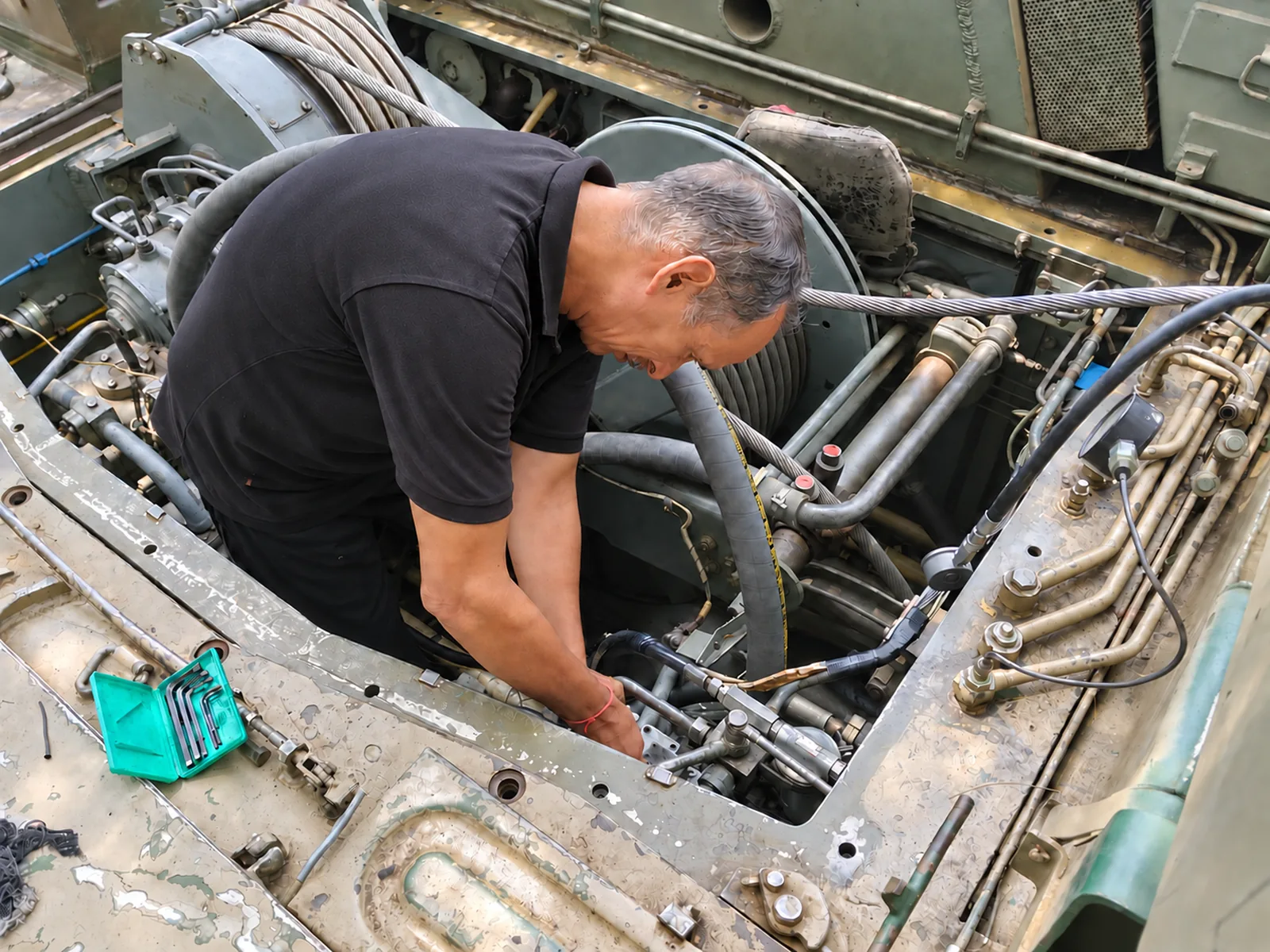 Technician working on hydraulic components in a specialised vehicle